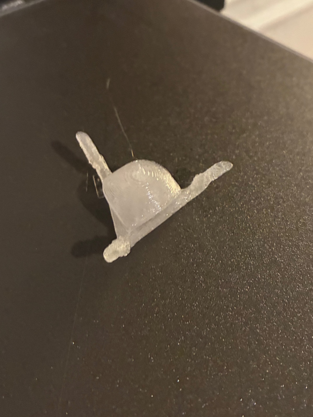 Small translucent 3D-printed corner foot part on a printer bed