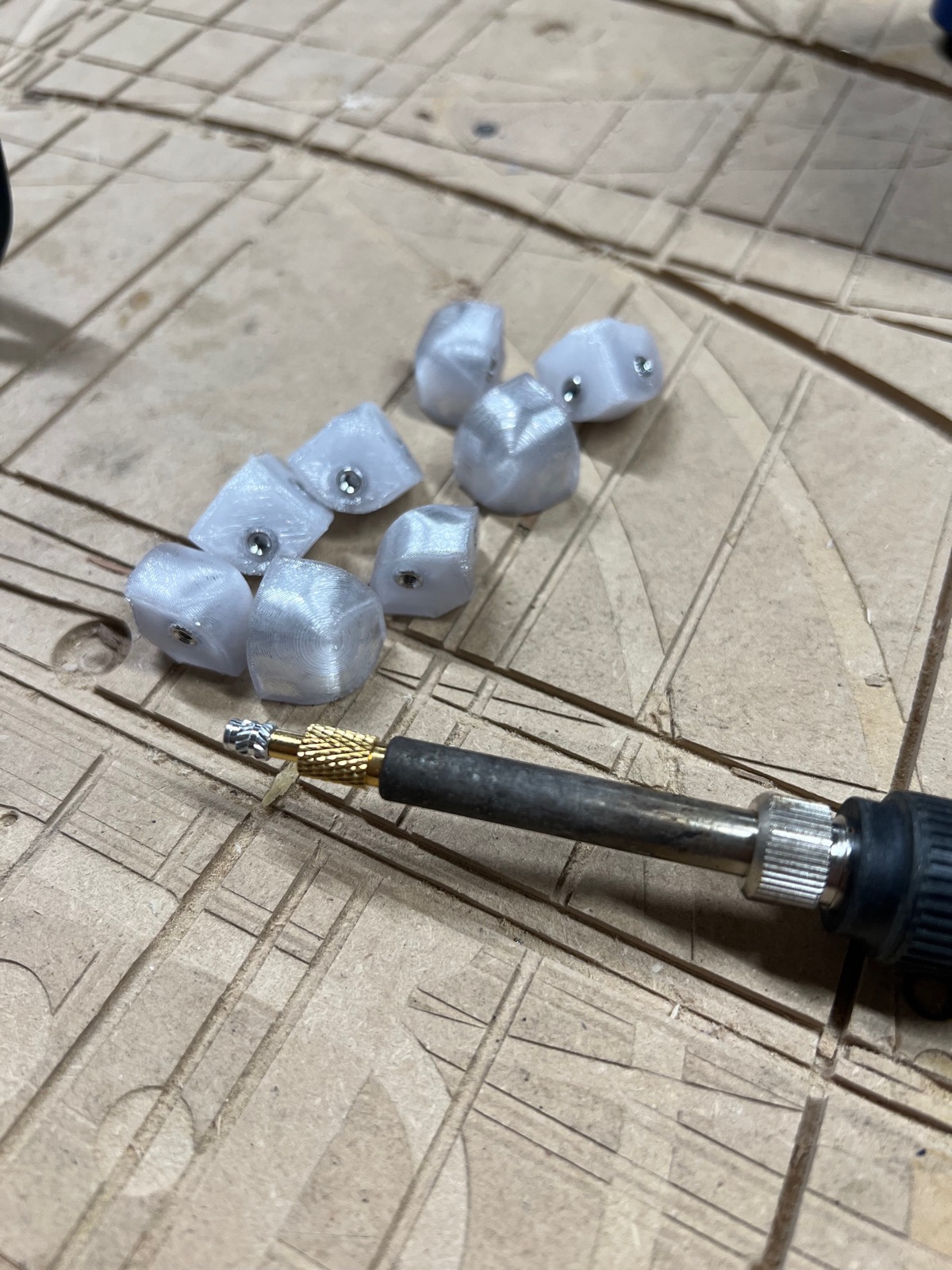 Translucent 3D-printed cube corner vertices beside a soldering iron