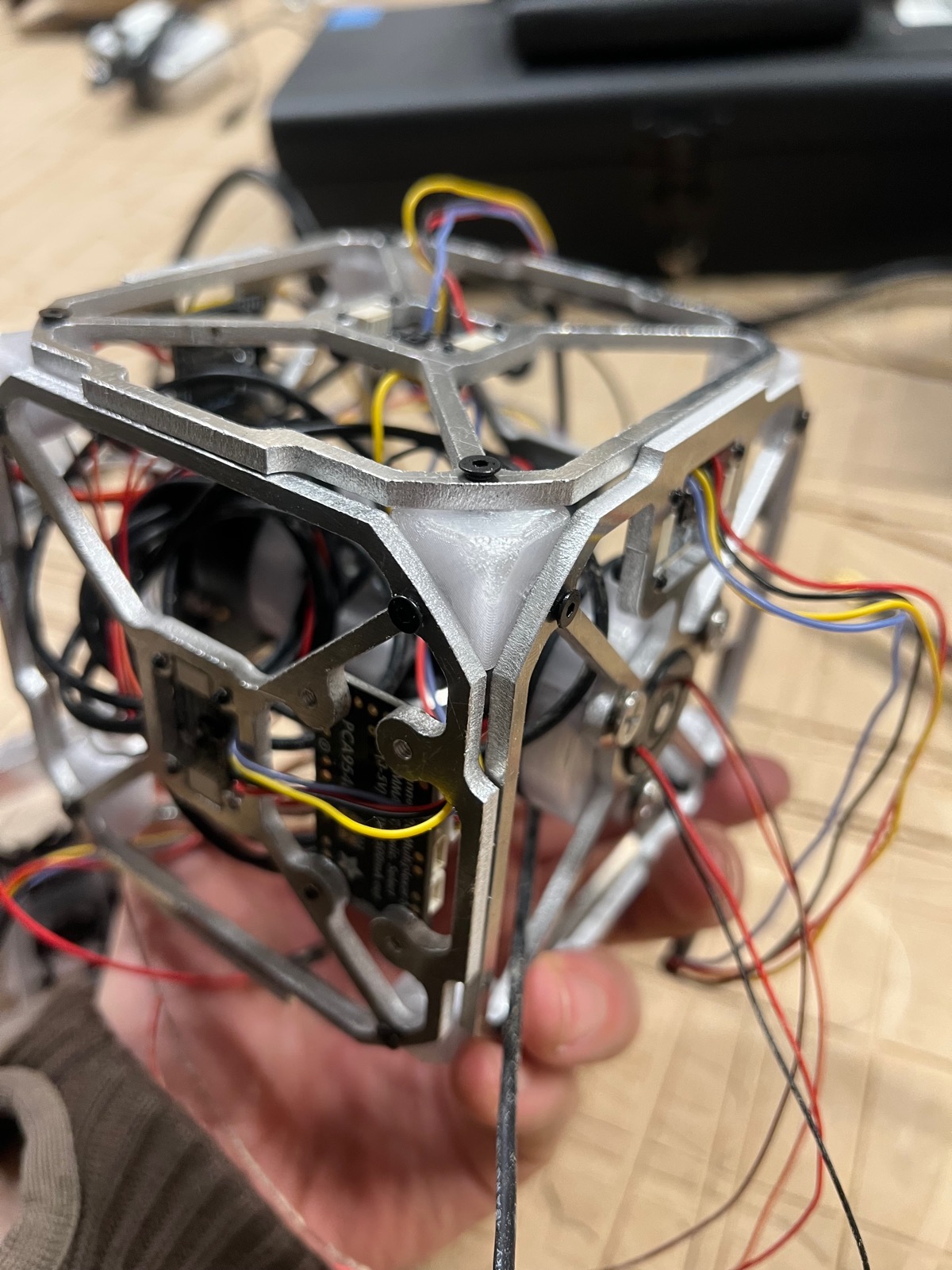 Assembled aluminum cube frame with motors and wiring, held in hand