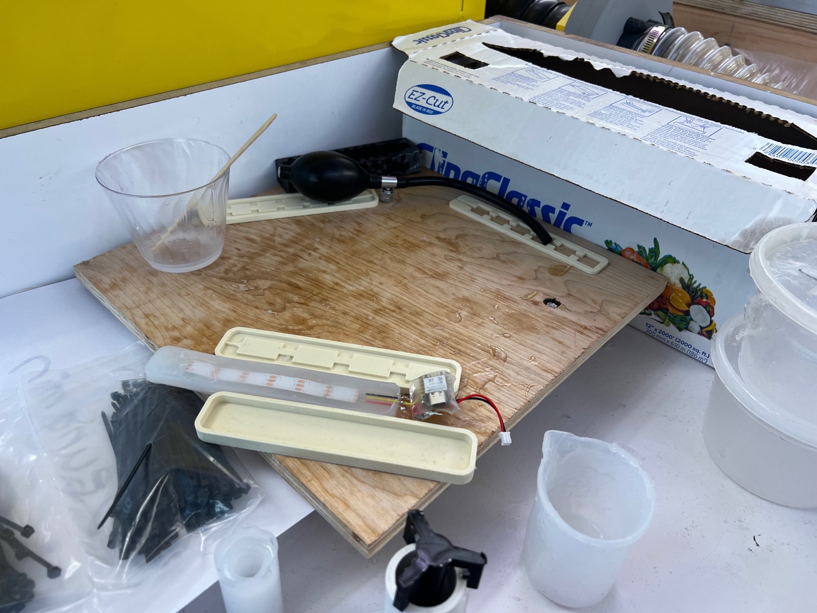Casting setup with molds, a hand bulb pump, and an LED strip
