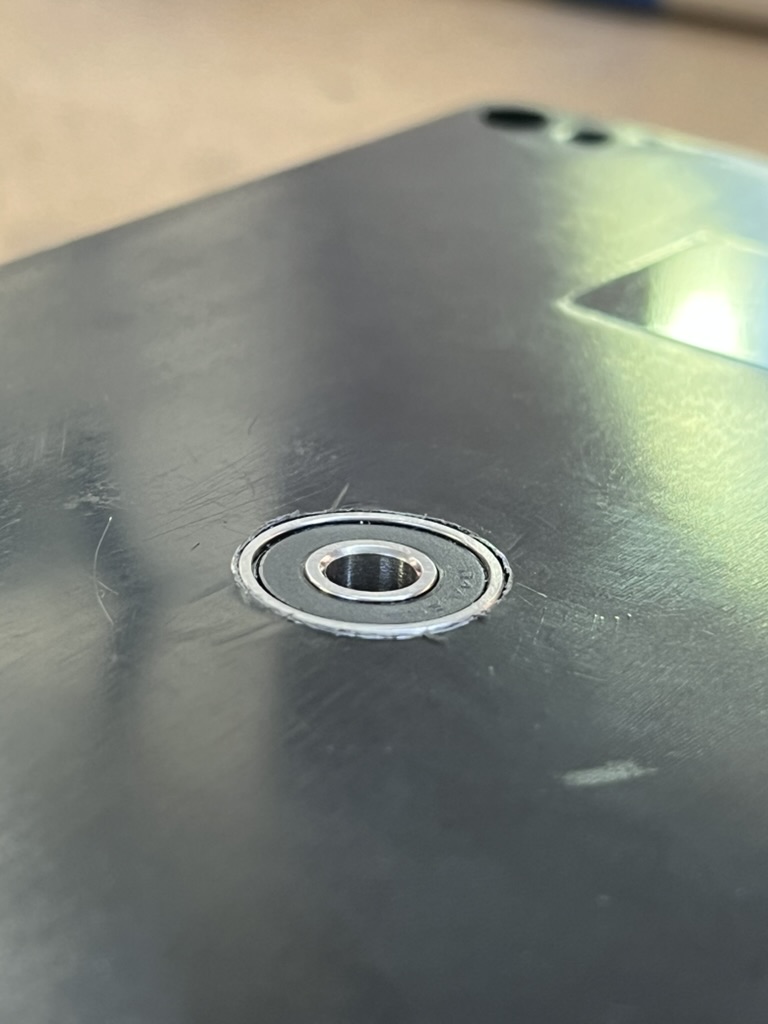 Close up of a small steel bearing pressed flush into the center hole of the black enclosure.