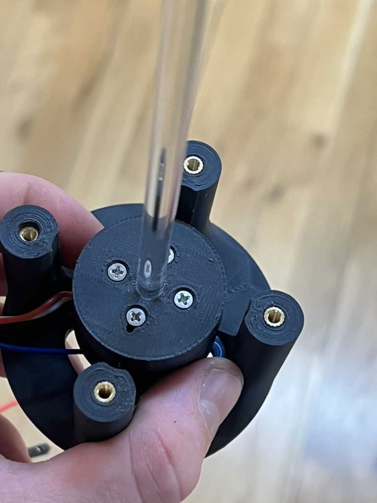 The top of the printed motor mount: three screws through the motor cap, the clear acrylic rod in the center, and brass heat set inserts in the four posts.